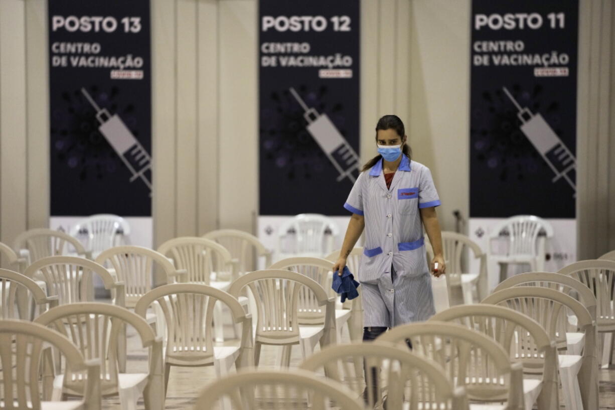 FILE - A worker disinfects chairs at a new vaccination center in Lisbon, Tuesday, Nov. 30, 2021. A pandemic-weary world faces weeks of confusing uncertainty as countries restrict travel and take other steps to halt the newest potentially risky coronavirus mutant before anyone knows just how dangerous omicron really is.