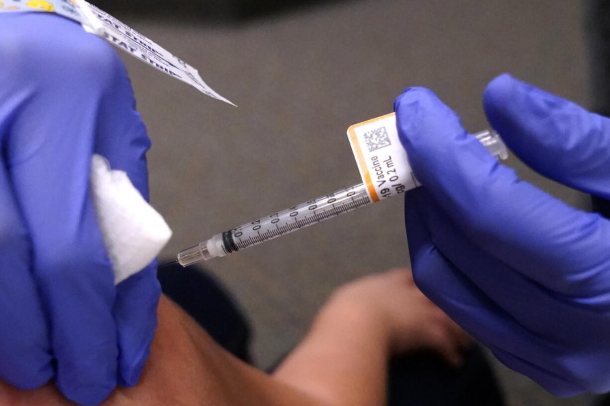 An eight-year-old child receives a second dose of the Pfizer COVID-19 vaccine at Northwest Community Church in Chicago, Saturday, Dec. 11, 2021.  Pfizer is adding an extra dose of its COVID-19 vaccine for babies and preschoolers enrolled in a study of the shots.  Pfizer and its partner BioNTech announced, Friday, Dec. 17,  they were adding a third dose to the study after a preliminary analysis found 2- to 4-year-olds didn't have as strong an immune response as expected.   (AP Photo/Nam Y.