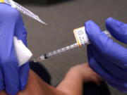 An eight-year-old child receives a second dose of the Pfizer COVID-19 vaccine at Northwest Community Church in Chicago, Saturday, Dec. 11, 2021.  Pfizer is adding an extra dose of its COVID-19 vaccine for babies and preschoolers enrolled in a study of the shots.  Pfizer and its partner BioNTech announced, Friday, Dec. 17,  they were adding a third dose to the study after a preliminary analysis found 2- to 4-year-olds didn't have as strong an immune response as expected.   (AP Photo/Nam Y.