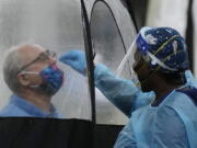 FILE - A man is tested for COVID-19, at a walk-up testing site run by Nomi Health, Dec. 28, 2021, in downtown Miami. More than a year after the vaccine was rolled out, new cases of COVID-19 in the U.S. have soared to the highest level on record at over 265,000 per day on average, a surge driven largely by the highly contagious omicron variant.