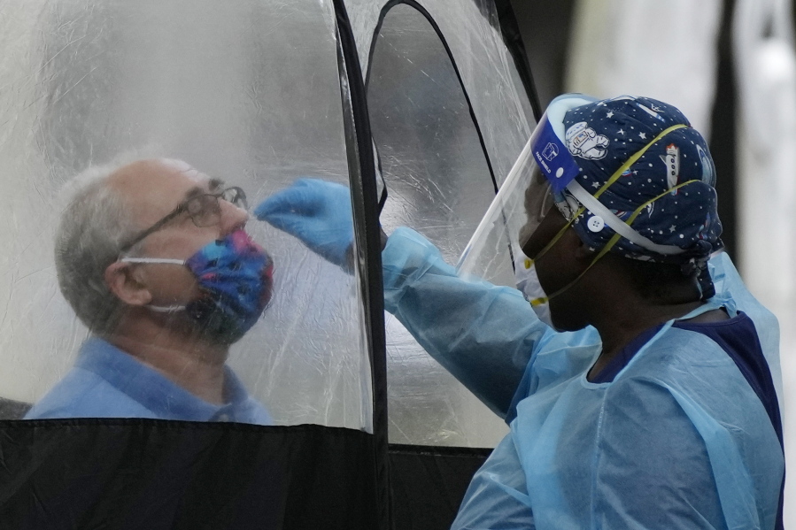 FILE - A man is tested for COVID-19, at a walk-up testing site run by Nomi Health, Dec. 28, 2021, in downtown Miami. More than a year after the vaccine was rolled out, new cases of COVID-19 in the U.S. have soared to the highest level on record at over 265,000 per day on average, a surge driven largely by the highly contagious omicron variant.