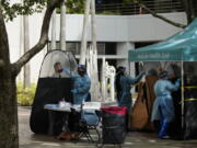 FILE - People are tested for COVID-19, at a walk-up testing site run by Nomi Health, Tuesday, Dec. 28, 2021, in downtown Miami. More than a year after the vaccine was rolled out, new cases of COVID-19 in the U.S. have soared to the highest level on record at over 265,000 per day on average, a surge driven largely by the highly contagious omicron variant.