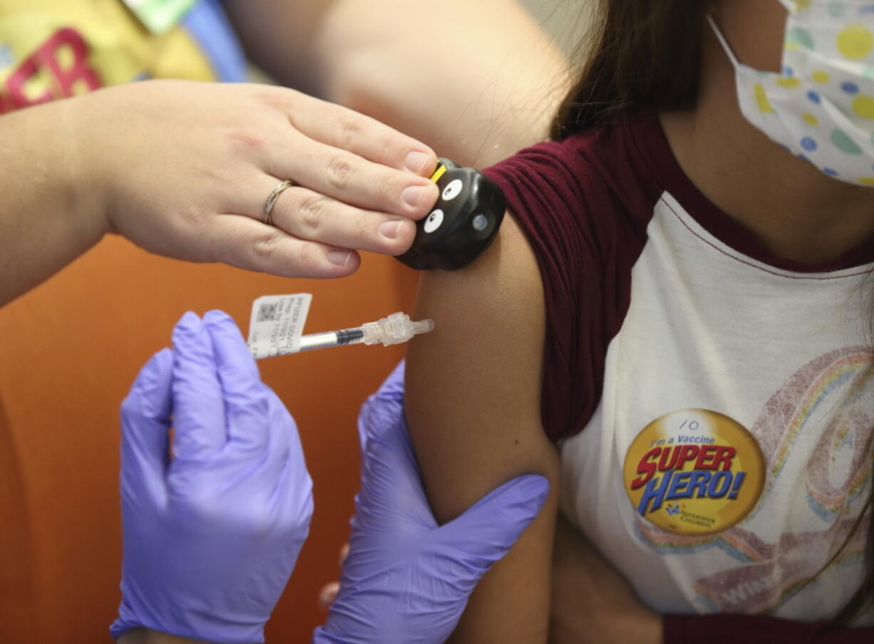 Parker McKenzie, 10, right, receives a Pfizer COVID-19 vaccine from nurse practitioner Amy Wahl with distraction help from certified child life specialist Haylee Rogers during the first COVID-19 vaccine clinic in Franklin County for children age 5-11 at Nationwide Children's Hospital in Columbus, Ohio Wednesday, Nov. 3, 2021. The omicron-fueled surge that is sending COVID-19 cases rocketing in the U.S. is putting children in the hospital in close to record numbers, and experts lament that most of the youngsters are not vaccinated.