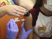 Parker McKenzie, 10, right, receives a Pfizer COVID-19 vaccine from nurse practitioner Amy Wahl with distraction help from certified child life specialist Haylee Rogers during the first COVID-19 vaccine clinic in Franklin County for children age 5-11 at Nationwide Children's Hospital in Columbus, Ohio Wednesday, Nov. 3, 2021. The omicron-fueled surge that is sending COVID-19 cases rocketing in the U.S. is putting children in the hospital in close to record numbers, and experts lament that most of the youngsters are not vaccinated.