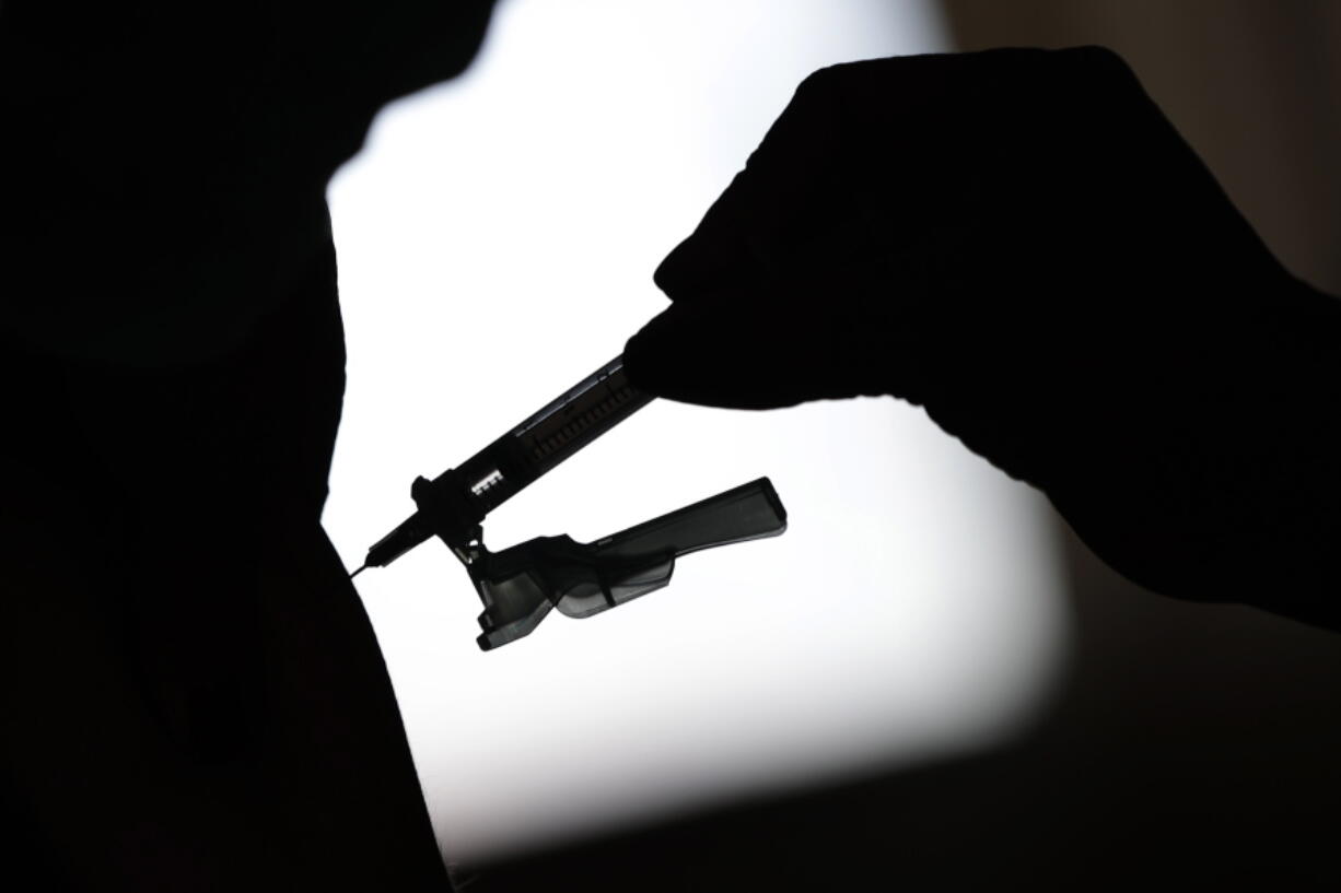 A health worker gives a shot of the Johnson & Johnson COVID-19 vaccine inside the Solidary Hands Shelter for the homeless in the poor neighborhood of Ceilandia in Brasilia, Brazil, in June.