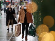 A woman wearing a face mask to guard against COVID-19 carries bags of shopping along Oxford Street in London, Monday, Dec. 27, 2021. In Britain, where the omicron variant has been dominant for days, government requirements have been largely voluntary and milder than those on the continent, but the Conservative government said it could impose new restrictions after Christmas.