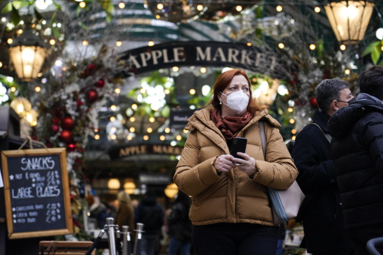 A woman wears a face mask as she walks in Covent Garden market, in London, Thursday, Dec. 16, 2021. The U.K. recorded the highest number of confirmed new COVID-19 infections Wednesday since the pandemic began, and England's chief medical officer warned the situation is likely to get worse as the omicron variant drives a new wave of illness during the Christmas holidays. The U.K. recorded 78,610 new infections on Wednesday, 16% higher than the previous record set in January.