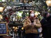 A woman wears a face mask as she walks in Covent Garden market, in London, Thursday, Dec. 16, 2021. The U.K. recorded the highest number of confirmed new COVID-19 infections Wednesday since the pandemic began, and England's chief medical officer warned the situation is likely to get worse as the omicron variant drives a new wave of illness during the Christmas holidays. The U.K. recorded 78,610 new infections on Wednesday, 16% higher than the previous record set in January.