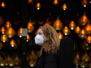 A woman wears a face covering as she passes a Christmas lights, in London, Wednesday, Dec. 22, 2021. British Prime Minister Boris Johnson said on Monday that his government reserves the "possibility of taking further action" to protect public health as Omicron spreads across the country.