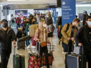 Holiday travelers wearing face masks line to check in at the Los Angeles International Airport in Los Angeles, Wednesday, Dec. 22, 2021. (AP Photo/Ringo H.W.