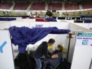 A woman receives Moderna COVID-19 vaccine as riders train at the National Velodrome in Saint-Quentin-en-Yvelines, west of Paris, France, Friday, Dec. 17, 2021. The government is holding a special virus security meeting Friday to address growing pressure on hospitals in France from rising infections.