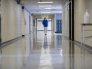 FILE - A middle school principal walks the empty halls of his school as he speaks with one of his teachers to get an update on her COVID-19 symptoms, Friday, Aug., 20, 2021, in Wrightsville, Ga. On Monday, Dec. 27, 2021, U.S. health officials cut isolation restrictions for Americans who catch the coronavirus from 10 to five days, and also shortened the time that close contacts need to quarantine. (AP Photo/Stephen B.