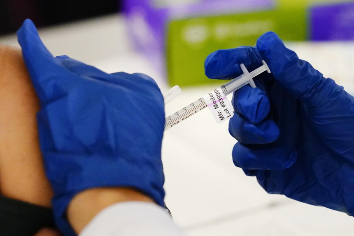 FILE - A health worker administers a dose of a Moderna COVID-19 vaccine during a vaccination clinic at the Norristown Public Health Center in Norristown, Pa., Tuesday, Dec. 7, 2021. The Centers for Disease Control and Prevention posted revised guidelines on Thursday, Dec. 23, that are loosening rules that call on health care workers to stay out of work for 10 days if they test positive for COVID-19. Those workers will be allowed to come back to work after seven days if they test negative and don't have symptoms.