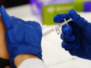 FILE - A health worker administers a dose of a Moderna COVID-19 vaccine during a vaccination clinic at the Norristown Public Health Center in Norristown, Pa., Tuesday, Dec. 7, 2021. The Centers for Disease Control and Prevention posted revised guidelines on Thursday, Dec. 23, that are loosening rules that call on health care workers to stay out of work for 10 days if they test positive for COVID-19. Those workers will be allowed to come back to work after seven days if they test negative and don't have symptoms.