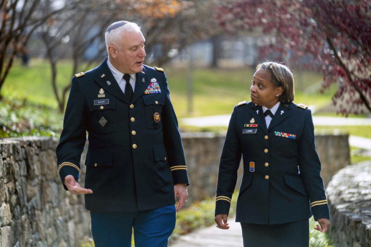 Head National Guard chaplain Col. Larry Bazer, deputy director of the chaplain office, left, and Chaplain Maj. A'Shellarien Lang, right, speak at the National Guard Bureau in Arlington, Va., Friday, Dec. 17, 2021.