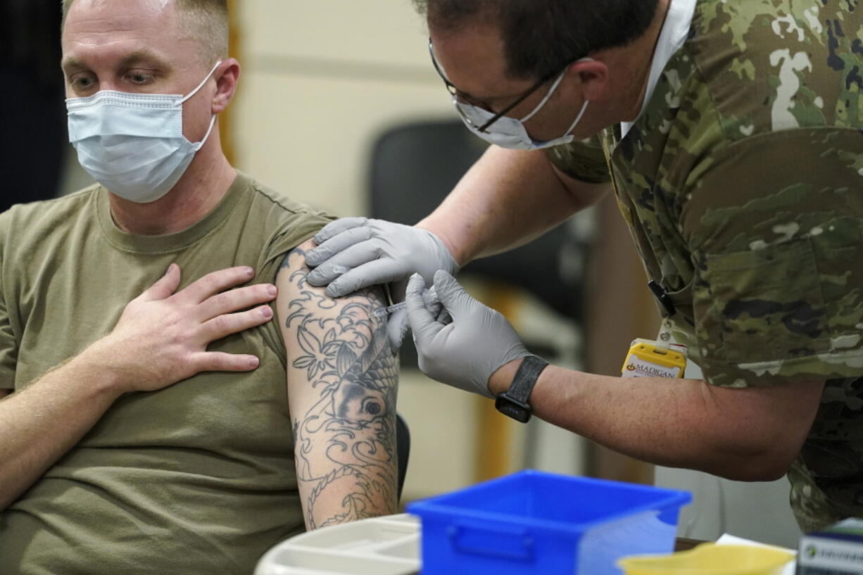 FILE - Staff Sgt. Travis Snyder, left, receives the first dose of the Pfizer COVID-19 vaccine given at Madigan Army Medical Center at Joint Base Lewis-McChord in Washington state, Dec. 16, 2020, south of Seattle. The Army says 98% of its active duty force had gotten at least one dose of the mandatory coronavirus vaccine as of this week's deadline for the shots.  (AP Photo/Ted S.