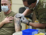 FILE - Staff Sgt. Travis Snyder, left, receives the first dose of the Pfizer COVID-19 vaccine given at Madigan Army Medical Center at Joint Base Lewis-McChord in Washington state, Dec. 16, 2020, south of Seattle. The Army says 98% of its active duty force had gotten at least one dose of the mandatory coronavirus vaccine as of this week's deadline for the shots.  (AP Photo/Ted S.