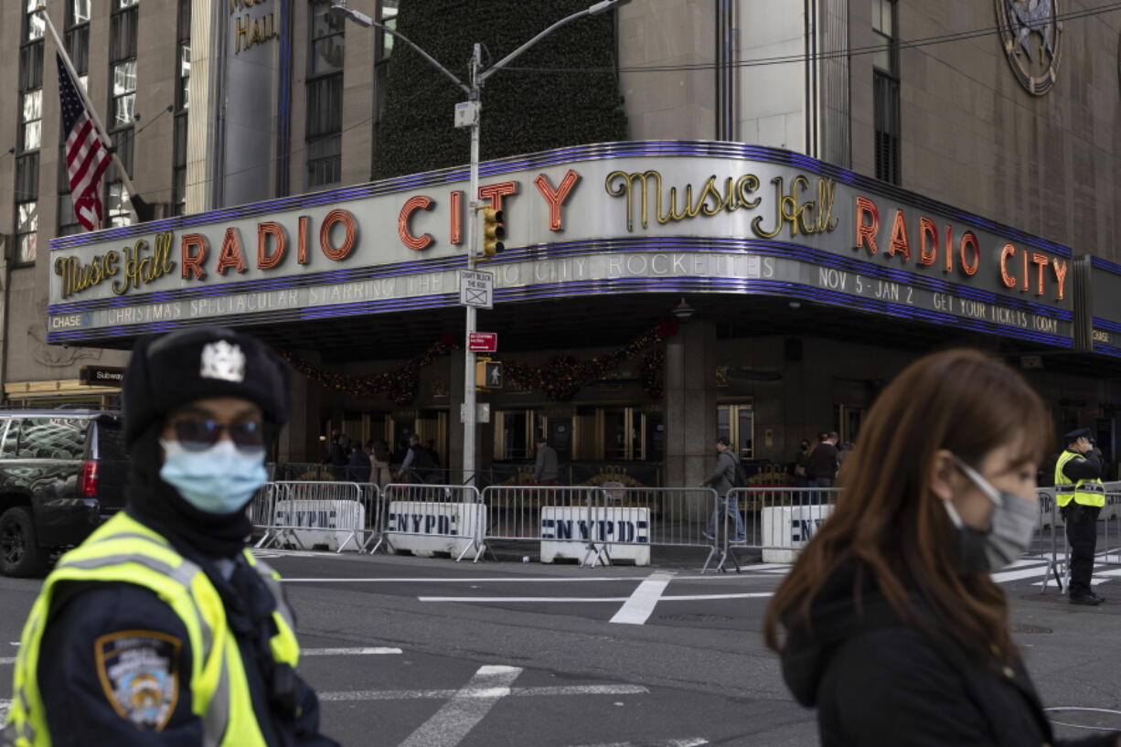 People stand in front of Radio City Music Hall after cancellations of The Rockettes performance due to COVID-19 cases on Friday, Dec. 17, 2021, in New York. New York City had been mostly spared the worst of the big surge in COVID-19 cases that has taken place across the northeastern and midwestern U.S. since Thanksgiving, but the situation has been changing rapidly in recent days.