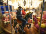 Children, some wearing face masks, enjoy a carousel ride at a Christmas fair in Bucharest, Romania, Saturday, Nov. 27, 2021. The Romanian capital will have three Christmas fairs open for public in the coming weeks and access to the venues will be conditioned by a COVID-19 green pas, proving the holder's vaccination or recovery after the infection.