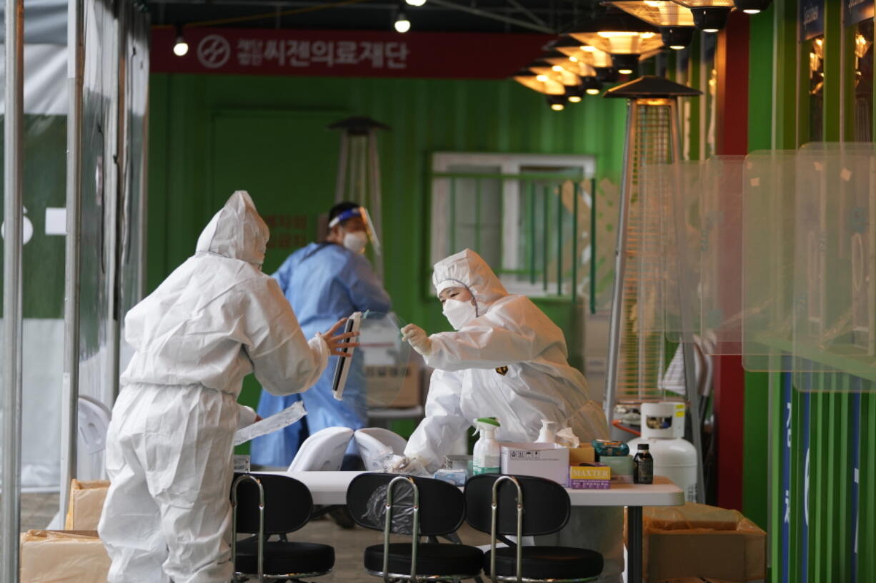 Medical workers wearing protective gear prepare to take samples at a temporary screening clinic for the coronavirus in Seoul, South Korea, Wednesday, Dec. 29, 2021.