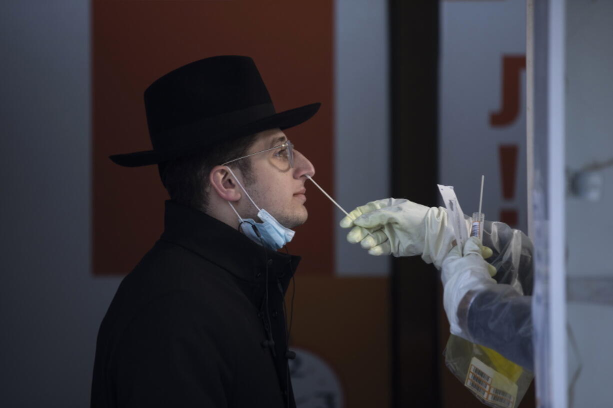 An Israeli health worker tests an unvaccinated ultra-Orthodox Jewish seminary student for COVID-19 at a coronavirus testing center in Jerusalem, Wednesday, Dec. 22, 2021. The student, who declined to give his name, said he didn't want to get vaccinated because he previously had COVID-19. Hundreds of thousands of ultra-Orthodox Jews in Israel have yet to receive their COVID shots. The group has some of the lowest vaccination rates in the country despite being pummeled by the virus throughout the pandemic.