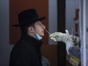 An Israeli health worker tests an unvaccinated ultra-Orthodox Jewish seminary student for COVID-19 at a coronavirus testing center in Jerusalem, Wednesday, Dec. 22, 2021. The student, who declined to give his name, said he didn't want to get vaccinated because he previously had COVID-19. Hundreds of thousands of ultra-Orthodox Jews in Israel have yet to receive their COVID shots. The group has some of the lowest vaccination rates in the country despite being pummeled by the virus throughout the pandemic.