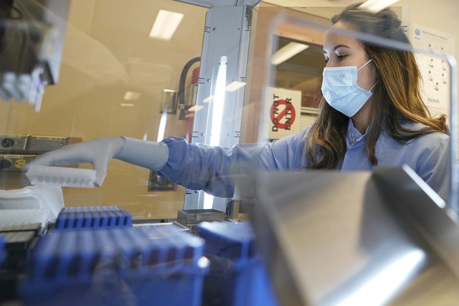 FILE - Kristin Grant, a microbiologist on the COVID-19 team at the Washington State Department of Health's Public Health Laboratory, loads samples that tested positive for COVID-19 into a machine that prepares them for automated genome sequencing, Tuesday, Dec. 7, 2021, in Shoreline, Wash. Data from the sequencing can then help determine which variant of the virus is present. (AP Photo/Ted S.