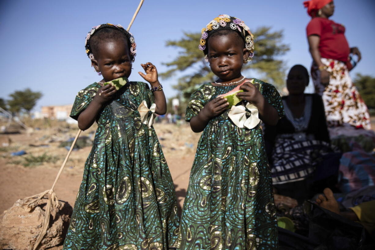 Twins eat slices of watermelon Nov. 25 at the Patte d'Oie district of Ouagadougou, Burkina Faso, where mothers of twins come to beg on the road. In Burkina Faso, a country with a strong belief in the supernatural, twins are regarded as children of spirits whose mothers were specially selected to bear them.