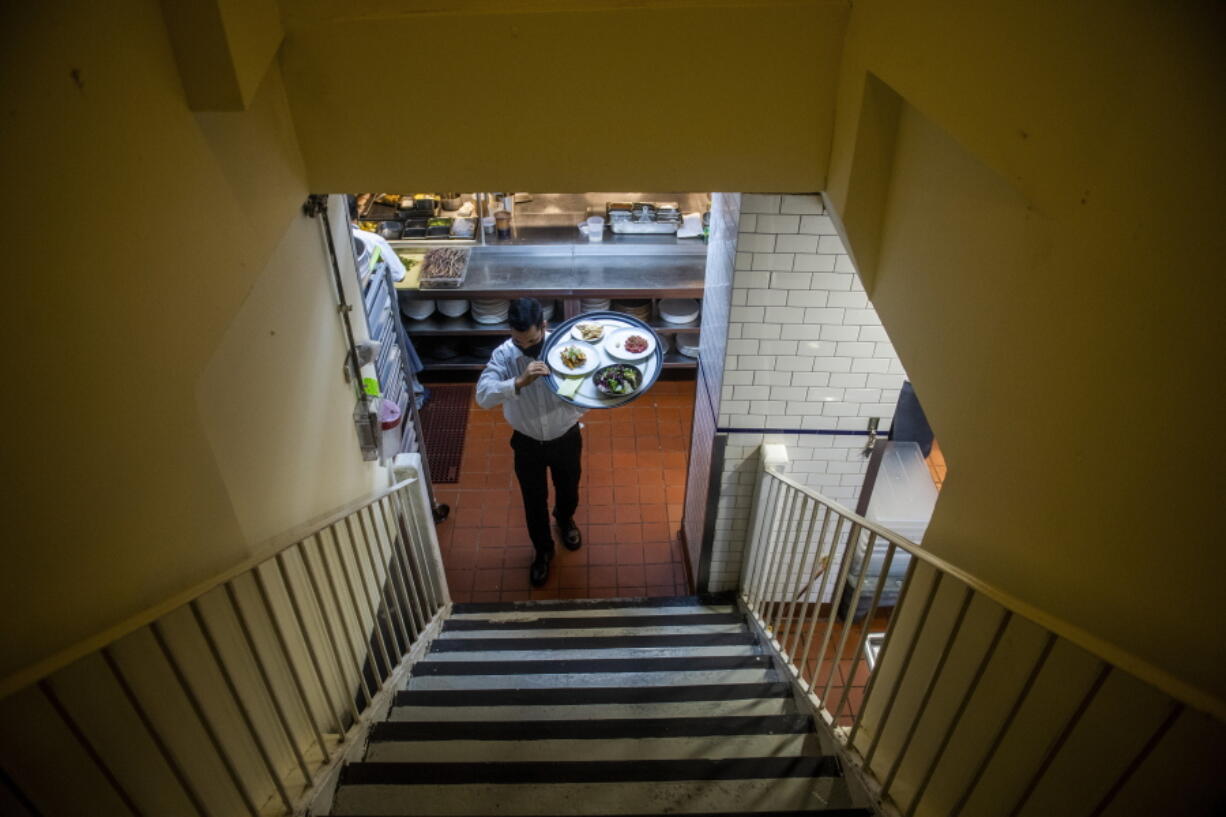 Muhammad Rahman delivers orders at Gotham restaurant on Tuesday, Dec. 14, 2021, in New York. When COVID-19 tore through the United States in March 2020, the recession it caused was brutal yet brief. Yet for much of 2021, the recovery was undermined by new threats: A surge in inflation that shrank the value of paychecks, hurt the least advantaged Americans most and posed a political threat to President Joe Biden and Democrats in Congress.