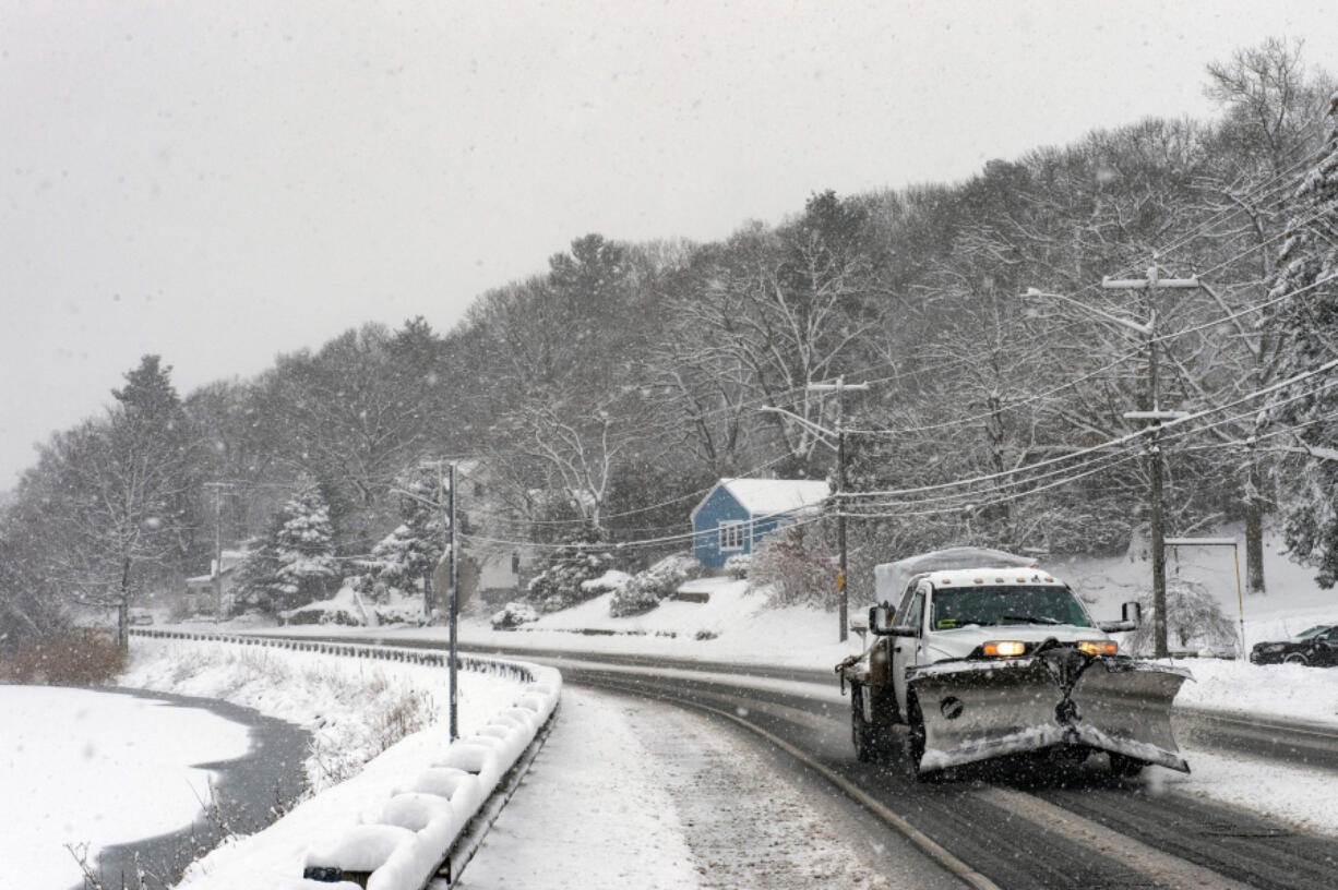 A plow drives down a recently plowed road by Birch Pond in Saugus, Massachusetts, on Jan. 7, 2022. Areas of New England received up to 12 inches of snow while many received 4 to 6 inches.