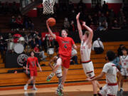 Beckett Currie of Camas drives to the hoop past R.A. Long's Aaron Ofstun during a non-league boys basketball game Wednesday at Longview.