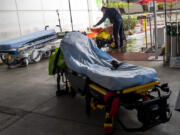 On a cold rainy day a paramedic places a blanket on a patient he has brought to the Emergency Department at Martin Luther King Jr. Community Hospital located on Wednesday, Dec. 29, 2021, in in the Willowbrook neighborhood of Los Angeles, California.