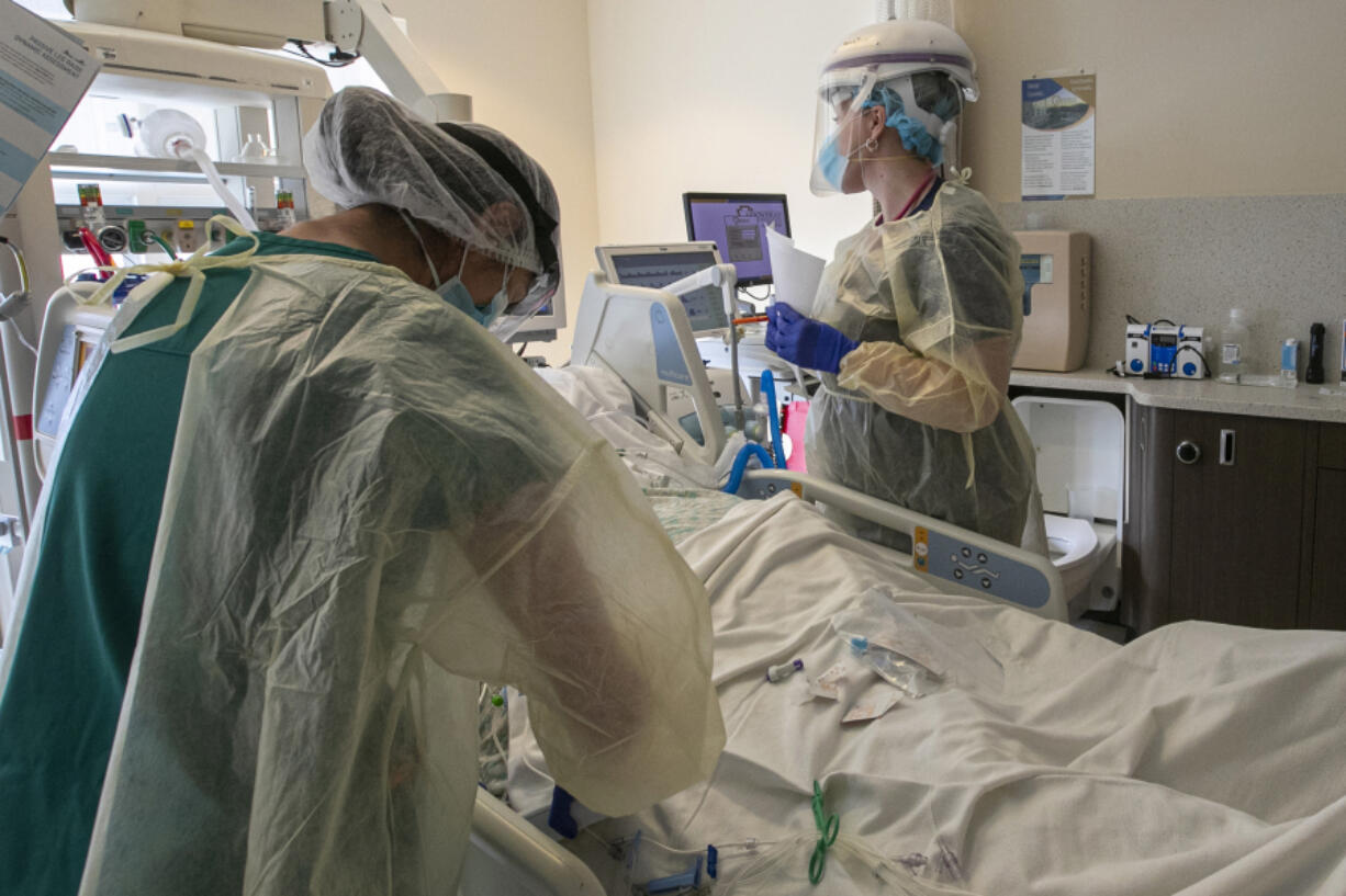 A nurse and respiratory therapist attend to a coronavirus patient in Intensive Care Unit of Arrowhead Regional Medical Center on Wednesday, Dec. 23, 2020 in Colton, California.