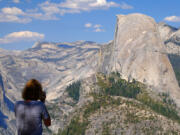 A visitor snaps photos of Half Dome from Washburn Point in Yosemite National Park on Aug. 4, 2021. The peak of Half Dome is over 8,000 feet above sea level.