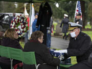 Linda Dunn, center, niece of USS Oklahoma sailor Daryle Artley, joins loved ones as Rear Adm. Scott Ruston, right, honors his memory at Park Hill Cemetery on Monday.