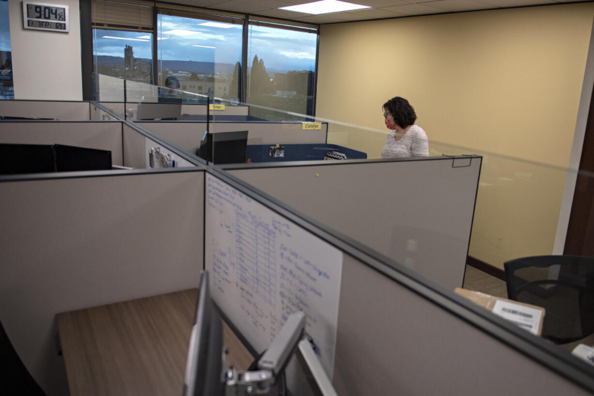 Stephanie McClintock of United Grain Corporation looks over some of the new desks with acrylic partitions for COVID-19 protection in the company's downtown office.