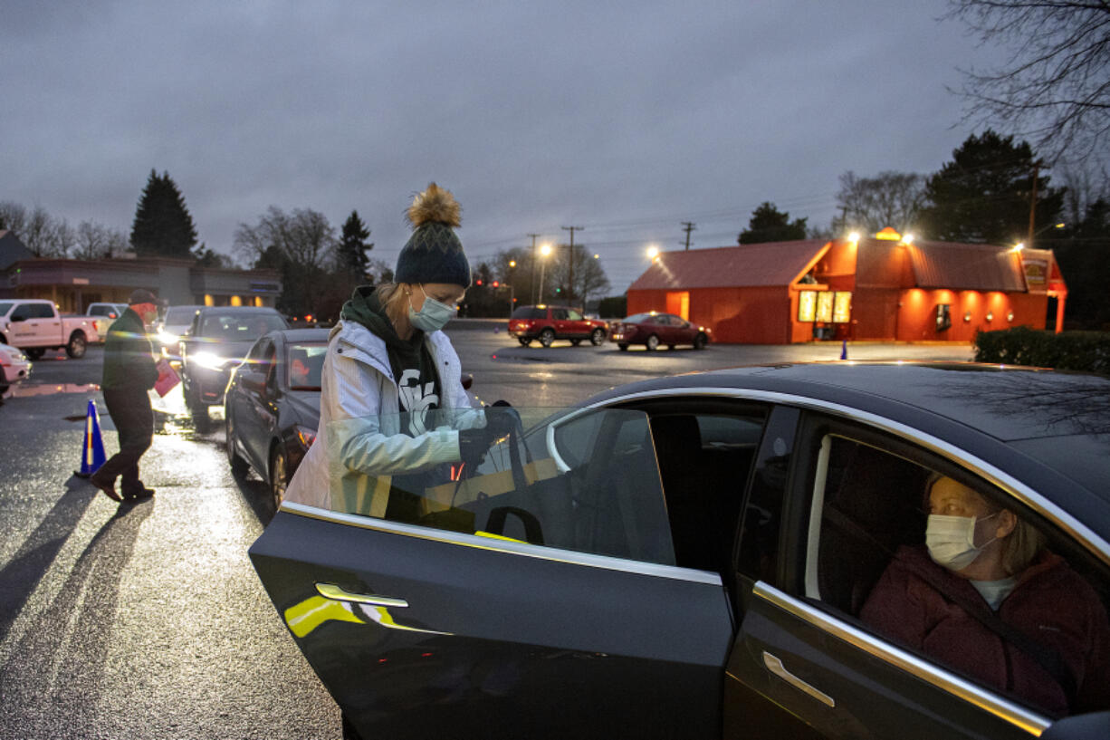 Jeana Fink of the Greater Vancouver Chamber lends a hand as Cathy Weeks of Vancouver picks up her Savor the Couve meal order at The Diner. Each week during the 16-week event, volunteers distribute food based on a weekly theme to folks who have purchased a Savor the Couve meal.