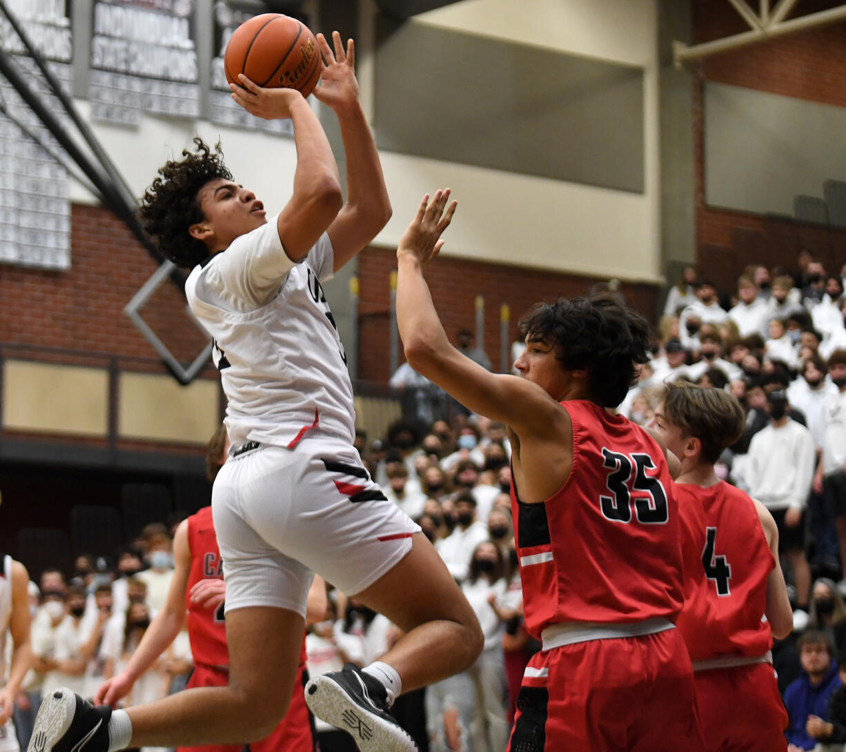 Union junior Yanni Fassillis, left, shoots the ball Wednesday, Jan. 12, 2022, during the Titans’ 72-60 win against the Papermakers at Union High School.