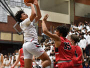 Union junior Yanni Fassillis, left, shoots the ball Wednesday, Jan. 12, 2022, during the Titans’ 72-60 win against the Papermakers at Union High School.