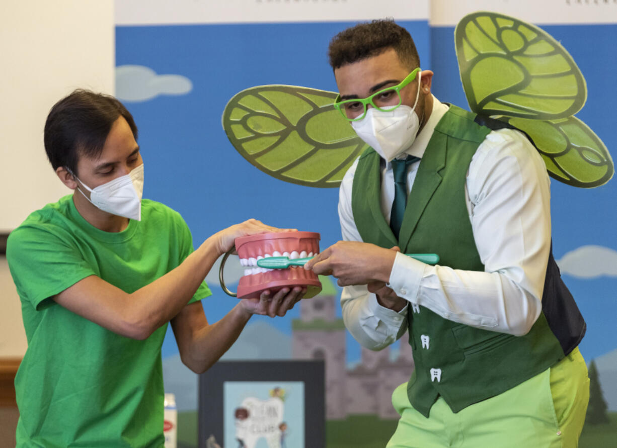 Malcolm Reed, right, dressed as the tooth fairy, brushes an oversized set of teeth while interpreter Rom Ngov, left, holds it Tuesday, during a presentation on brushing teeth by Delta Dental of Washington at the Washington School for the Deaf in Vancouver. The duo reminded the students -- and us, too -- to brush in circles, not just up and down.