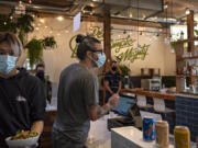 Stephen Chan of Mighty Bowl, left, serves up a lunch order as owner Steve Valenta chats with a customer in downtown Vancouver. In the fourth quarter of last year, Valenta's costs for food increased 24 percent. They had been steadily rising throughout the pandemic. His costs for to-go packaging rose 60 percent.