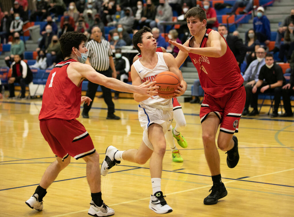 Ridgefield's Ramon Soto (2) is defended by R. A. Long's Jake Gabbard (1) and Jaxon Cook (21) as he attempts to drive towards the basket during the third quarter at Ridgefield High School on Thursday, January 27, 2022.