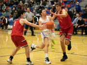 Ridgefield's Ramon Soto (2) is defended by R. A. Long's Jake Gabbard (1) and Jaxon Cook (21) as he attempts to drive towards the basket during the third quarter at Ridgefield High School on Thursday, January 27, 2022.