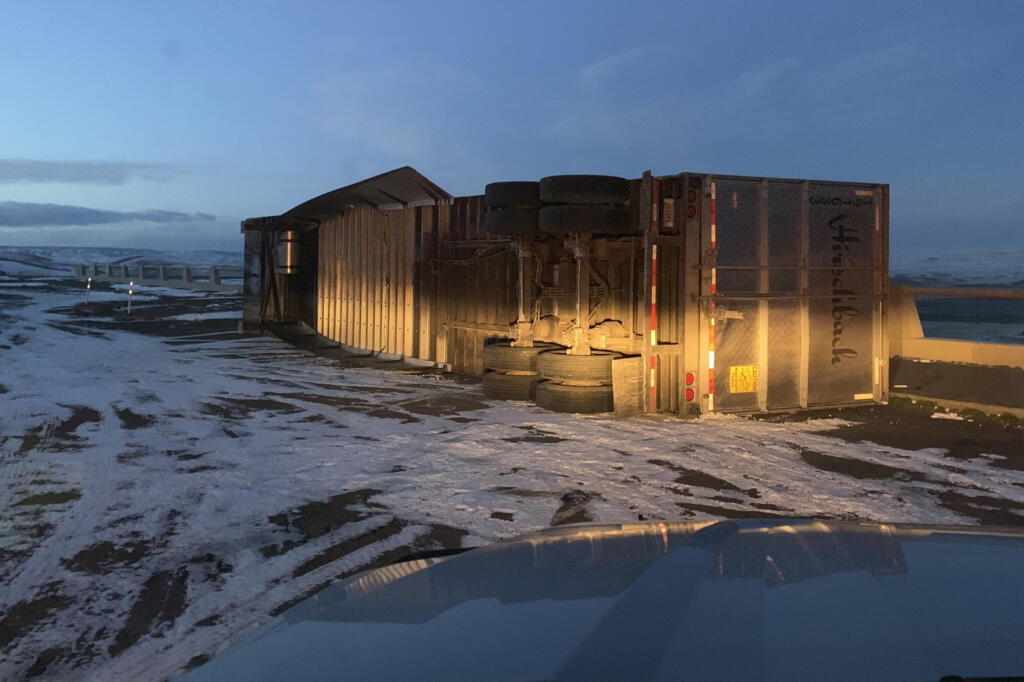 In this photo provided by the Oregon Department of Transportation, a truck is on its side after being blown over on Interstate 84 near a viewpoint in Cabbage Hill, Ore., Monday, Jan. 3, 2022. Heavy snow and high winds forced officials to close dozens of state roads in eastern Oregon on Monday and Interstate 84 was shut down through the Columbia River Gorge, while blowing snow also closed a major road over the Cascade Mountains in Washington.