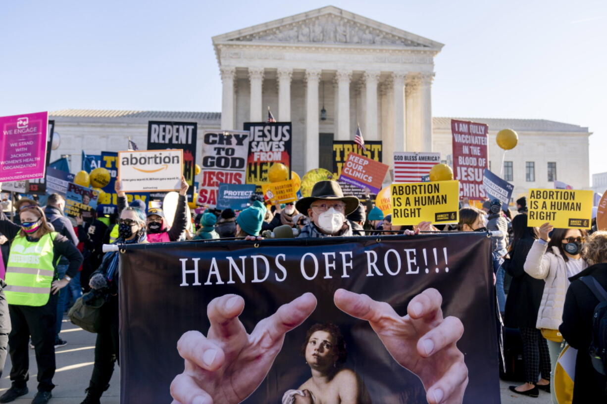 FILE - Stephen Parlato of Boulder, Colo., holds a sign that reads "Hands Off Roe!!!" as abortion rights advocates and anti-abortion protesters demonstrate in front of the U.S. Supreme Court, on Dec. 1, 2021, in Washington. With Roe v.