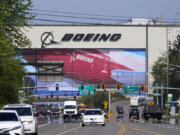 Traffic drives in view of a massive Boeing Co. production plant, where images of jets decorate the hangar doors, Friday, April 23, 2021, in Everett, Wash. .