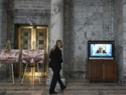 A Senate security worker walks near a video display outside the Senate chamber showing Washington Gov. Jay Inslee testifying remotely at a committee hearing on a bill that would make it a gross misdemeanor for elected officials or candidates to knowingly lie about election outcomes if those claims result in violence, Friday, Jan. 28, 2022, at the Capitol in Olympia, Wash. (AP Photo/Ted S.