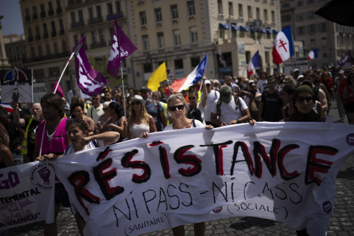 FILE - Protesters march during a demonstration to denounce a COVID-19 health pass needed to access restaurant, long-distance trains and other venues. in Marseille, southern France, Saturday, Aug. 14, 2021. The run-up to the April election comes in a context of mounting violence targeting elected officials in France, with holders of public officers targeted for their politics and by opponents of COVID-19 vaccinations restrictions.