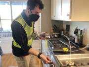 In this photo provided by climate scientist Rob Jackson, researcher Eric Lebel samples natural gas from a stove in Stanford, Calif., in 2021. According to a study published Thursday, Jan. 27, 2022, in the journal Environmental Science & Technology, gas stoves are worse for the climate than previously thought because of constant tiny methane leaks even while they're off.