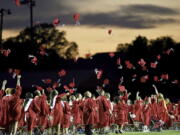 FILE - Red mortarboards fly into the evening sky at Heritage High School's commencement ceremony Friday, July 24, 2020, in Maryville Tenn.  High school graduation rates dipped in at least 20 states after the first full school year disrupted by the pandemic, according to a new analysis by Chalkbeat.